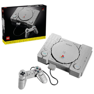 Verpackung des LEGO PlayStation-Sets neben der aus LEGO Steinen gebauten originalen PlayStation-Konsole und dem kabelgebundenen Controller.