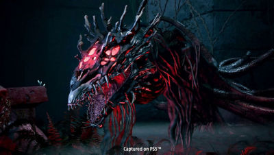 Nahaufnahme einer außerirdischen Kreatur, die leuchtend rote Körperteile besitzt sowie ihre scharfen Zähne in einem offenen Maul zur Schau stellt.