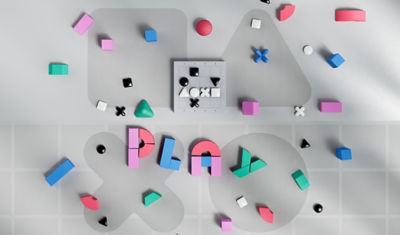 Silicone shapes alongside multicoloured magnetic blocks spelling the word Play, and black and white game pieces