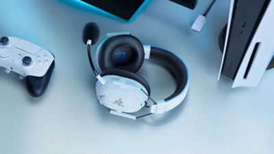Razer BlackShark Headset laying flat on a desk surrounded by accessories and PS5