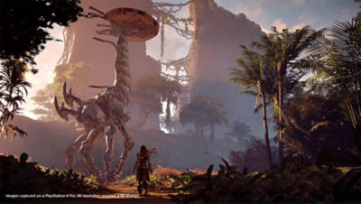 PS4 Horizon Zero Dawn Complete Edition screenshot featuring Aloy observing a Tallneck machine as she walks through a lush forest 