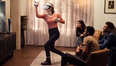 A woman plays PS VR2 with her friends.