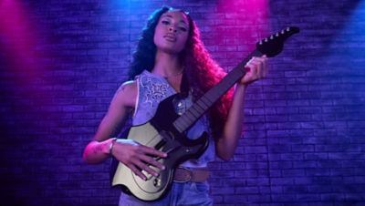 Player posing confidently with the black Riffmaster guitar controller under purple stage lighting.
