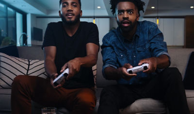 Two people playing PlayStation 5 together on the couch